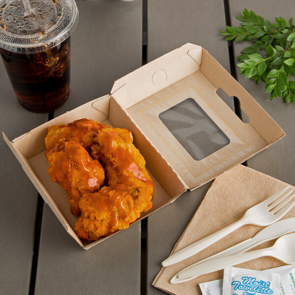 A Bagcraft Eco-Flute take-out box with chicken wings and a drink on a table.
