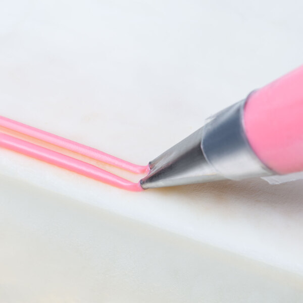 A close-up of an Ateco 2-Hole Piping Tip being used to draw a line on a cake.