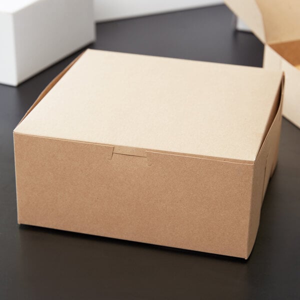 A Kraft bakery box with a white lid on a table.