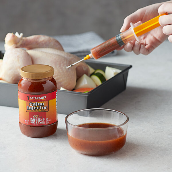 A person using a Cajun Injector to put hot liquid into a chicken.