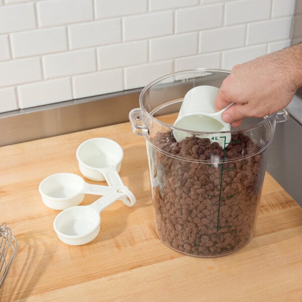 A person pouring chocolate chips into a Rubbermaid measuring cup.