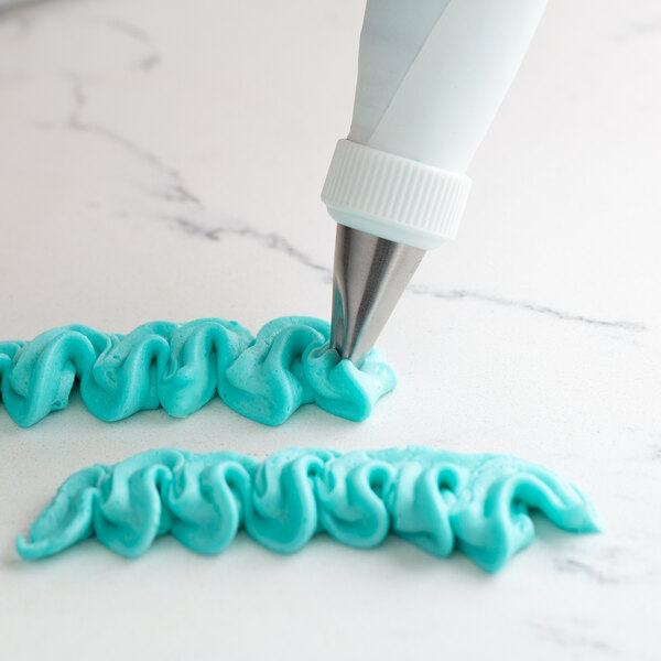 Blue frosting being piped onto a cake from a pastry bag using an Ateco curved petal piping tip.