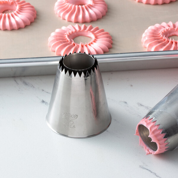 A close-up of a pastry cone with pink frosting in a circle.