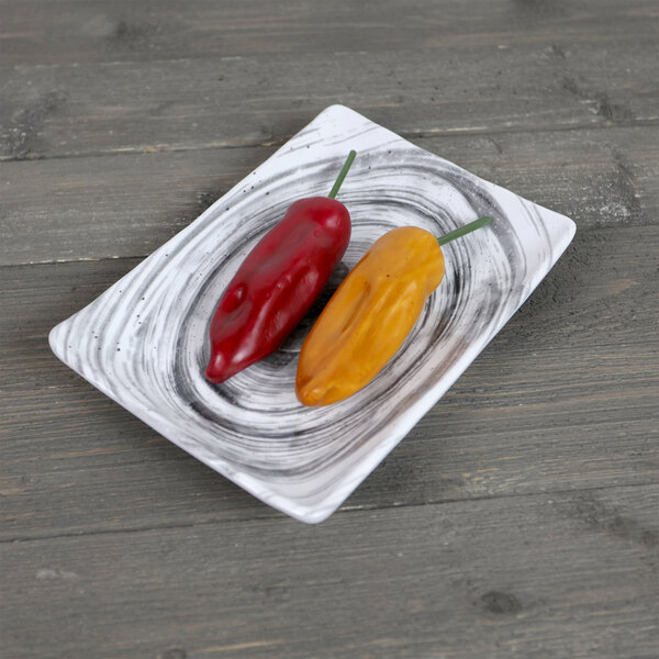A red and yellow pepper on an Elite Global Solutions Van Gogh black rectangular melamine plate.