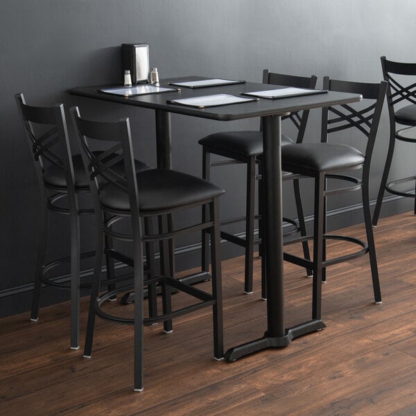 A black metal Lancaster Table & Seating bar table with a Lancaster Table & Seating black cast iron table base.
