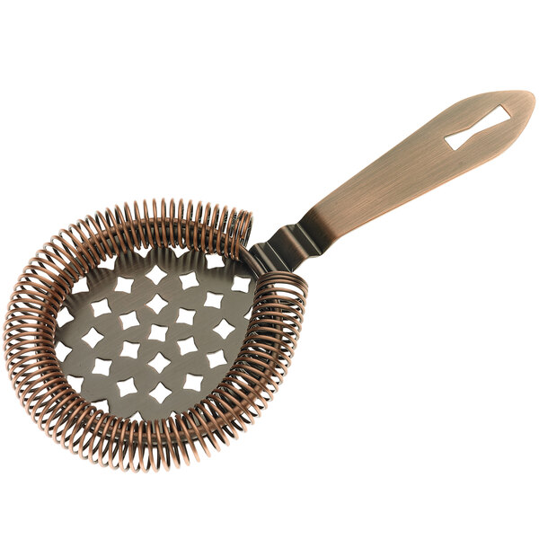 An antique copper-plated metal Barfly Hawthorne strainer with a handle and a metal coil with holes.