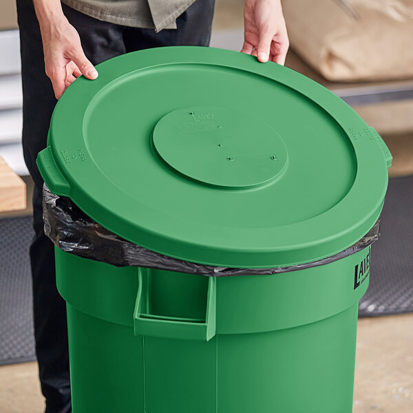A person holding a Lavex green commercial trash can lid.