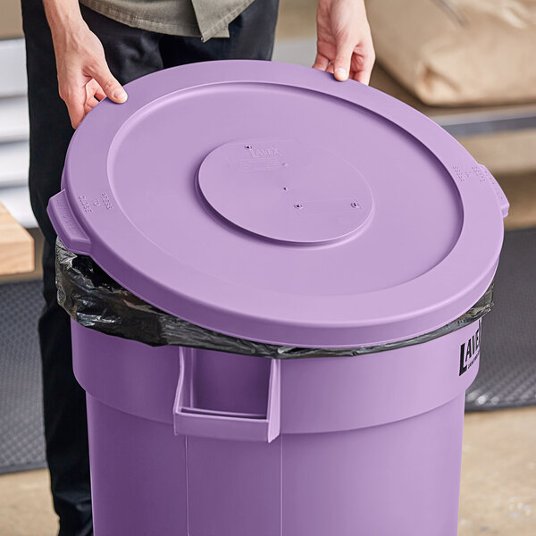 A person holding a Lavex purple round commercial trash can lid.