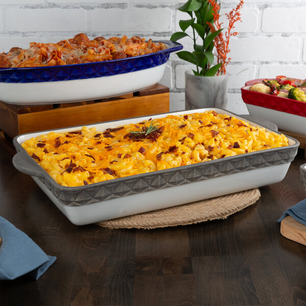A group of Tuxton rectangular casserole dishes on a table with macaroni and cheese.