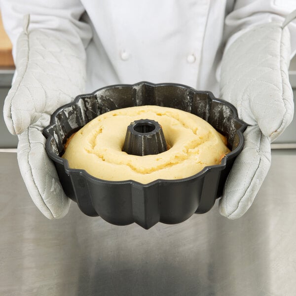 A person holding a Chicago Metallic fluted Bundt cake pan with a cake in it.