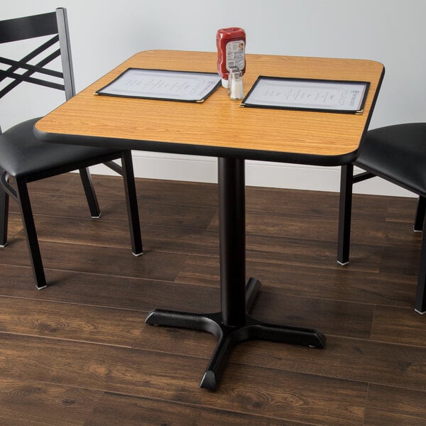 A Lancaster Table & Seating table with a reversible walnut and oak table top on a cross cast iron base.