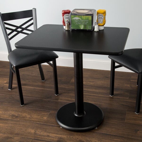 A Lancaster Table & Seating standard height table with a reversible cherry/black table top on a round cast iron base plate.