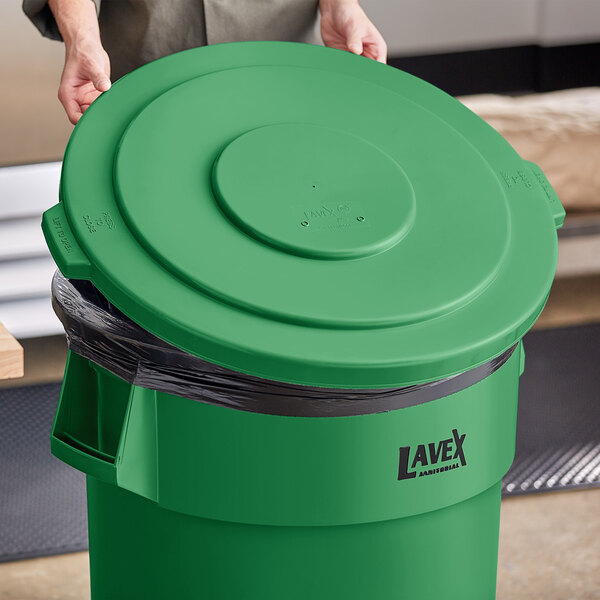 A woman holding a green Lavex commercial trash can lid.