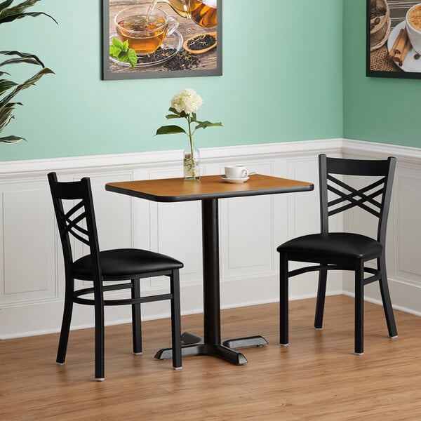 A Lancaster Table & Seating Standard Height Table with a reversible walnut and oak table top on a table with two chairs.