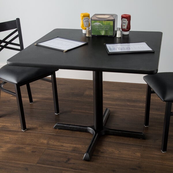 A table with a reversible cherry and black table top, a menu, and a chair.