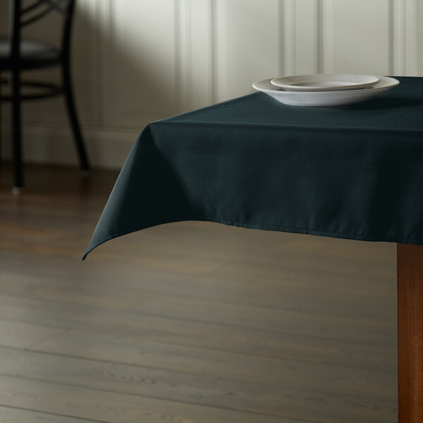 A table with a hunter green Intedge cloth table cover and a plate on it.