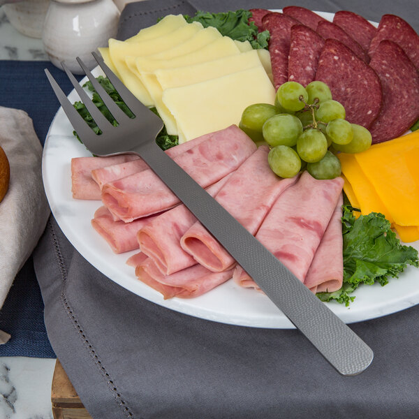 A plate of meat and cheese with an American Metalcraft hammered stainless steel cold meat fork.