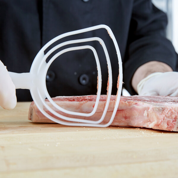 A person using a Dexter-Russell bone dust scraper to cut meat.