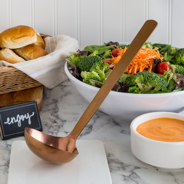 A bowl of salad with a Hammered Bronze Vintage Ladle.