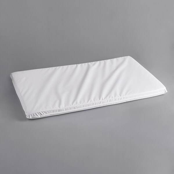 A white rectangular L.A. Baby crib mattress on a gray surface.