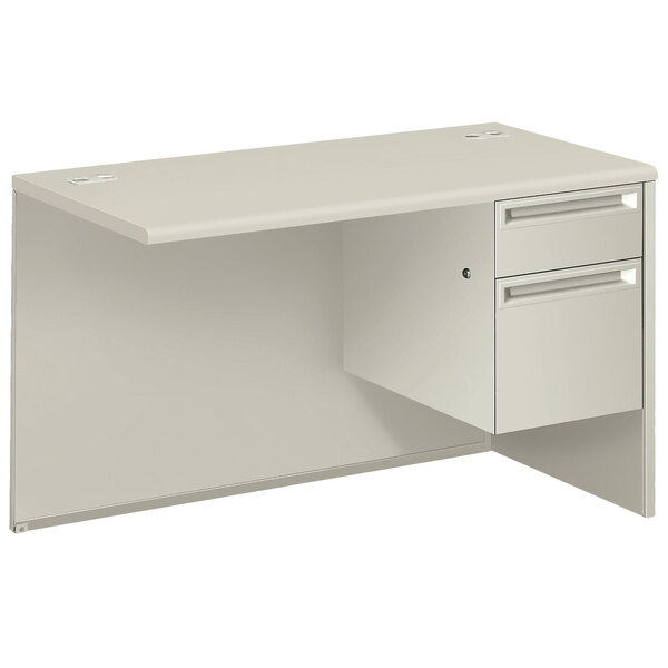 A silver mesh and light gray laminate HON pedestal workstation return with drawers.