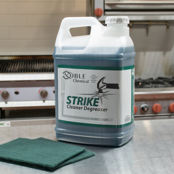 A large plastic container of Noble Chemical Strike All Purpose Concentrated Cleaner Degreaser on a counter.