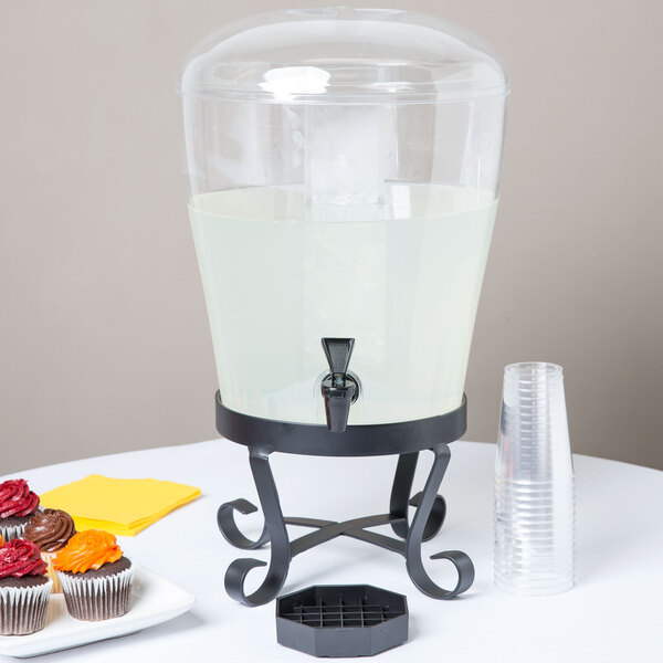 A clear plastic Cal-Mil beverage dispenser with a white liquid inside on a table.