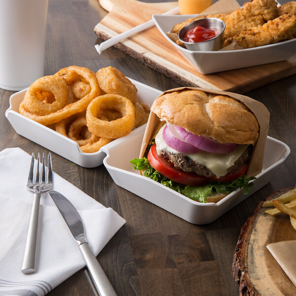 A Tablecraft white melamine burger box server on a table with a tray of food including a burger and fries.