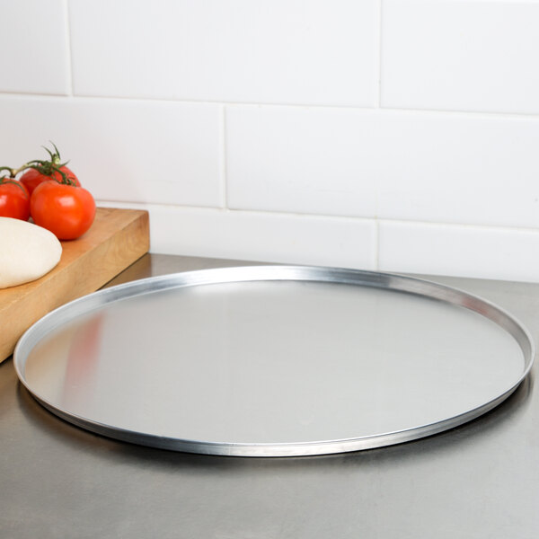 An American Metalcraft aluminum pizza pan on a counter.