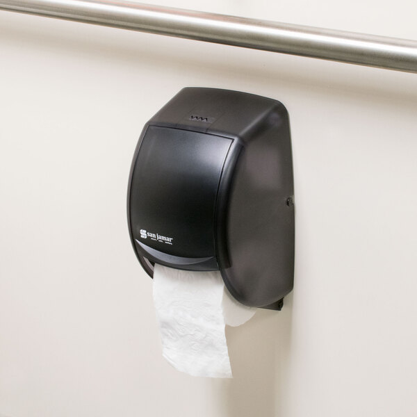 A black San Jamar Duett Classic toilet paper dispenser on a wall.