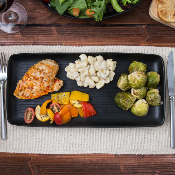A TuxTrendz Zion matte black china tray with food on a table.