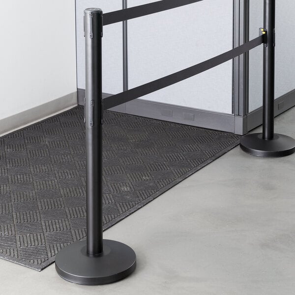 A Lancaster Table & Seating black stanchion with dual black retractable belts.