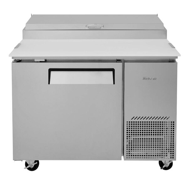 A white Turbo Air Super Deluxe refrigerated pizza prep table with a door on wheels.