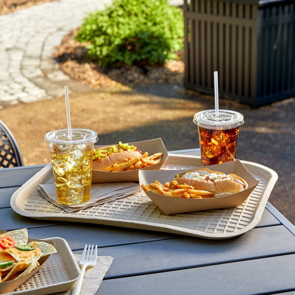 A tray of food on a table with a hot dog, fries, and a drink in a plastic cup with a straw.