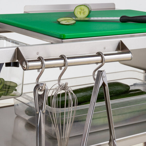 A Metro stainless steel utensil bar with a cutting board and cucumbers on it.