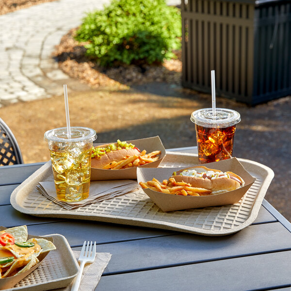 A tray of food on a table with a hot dog, fries, and a drink in a plastic cup with a straw.