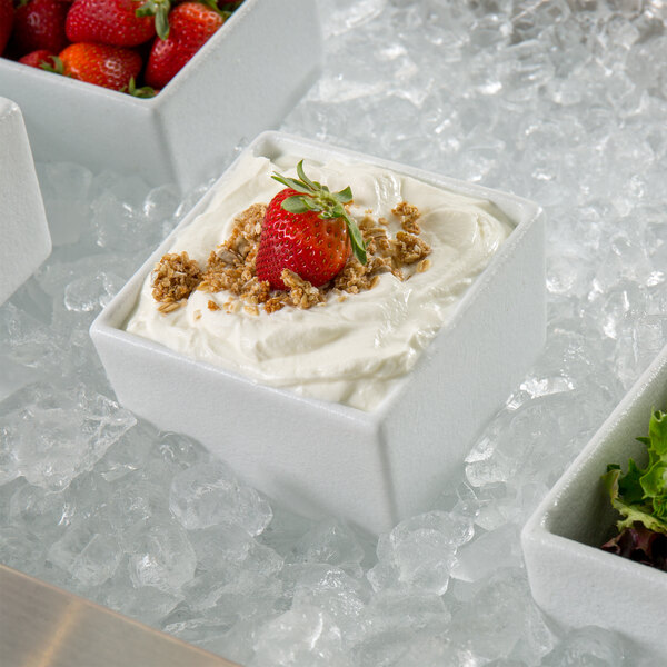 A white G.E.T. Enterprises Bugambilia straight-sided square salad bowl with strawberries and granola on top.