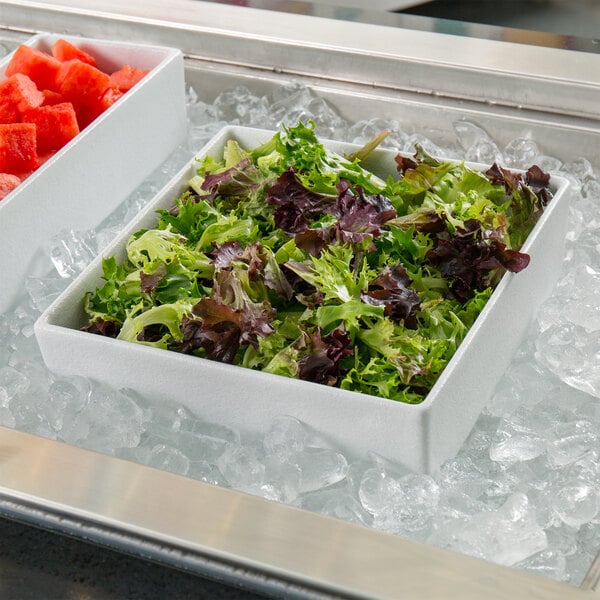 A white G.E.T. Enterprises Bugambilia salad bowl on ice with lettuce in it.