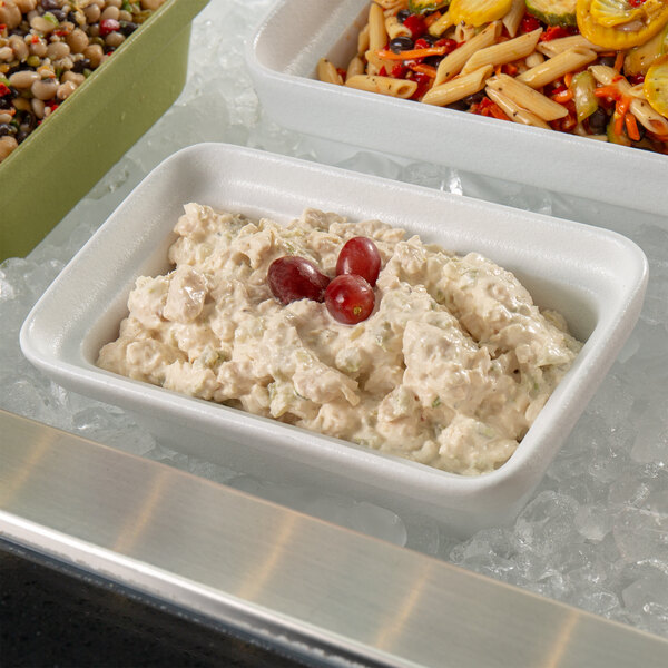 A white G.E.T. Enterprises Bugambilia rectangular china bowl filled with food on a counter in a salad bar.