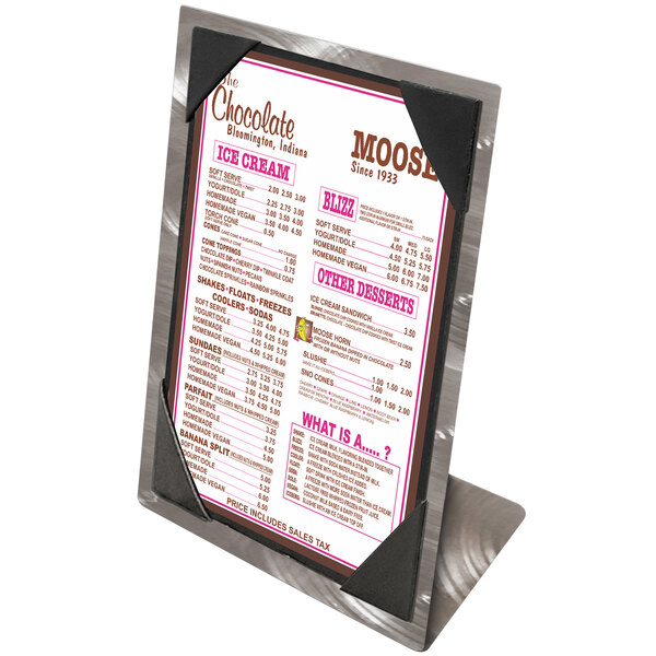 An Alumitique aluminum table tent with swirl picture corners holding a menu on a counter.