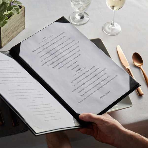A person holding a H. Risch, Inc. Oakmont menu with a knife and fork.