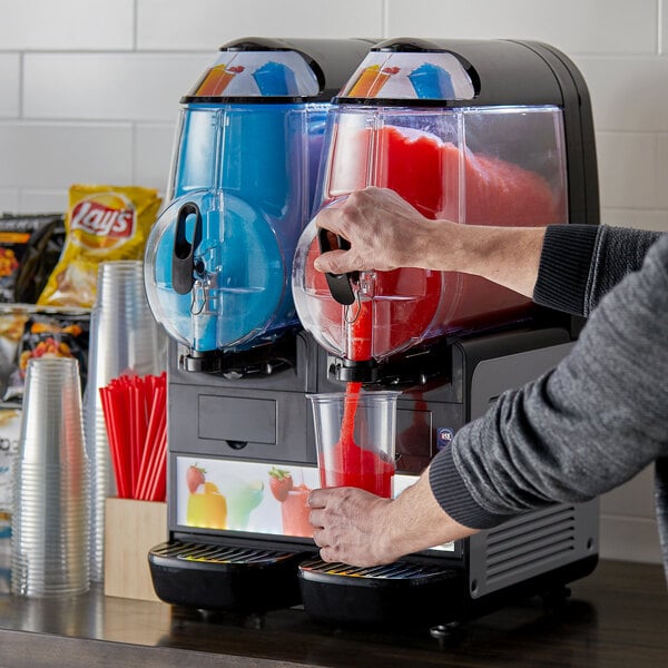 A person pouring a drink into a Vollrath frozen beverage machine.