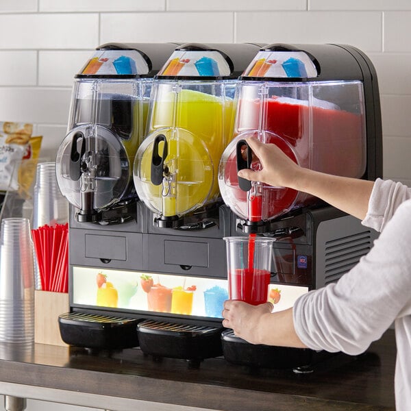 A woman pouring red liquid into a Vollrath frozen beverage machine.