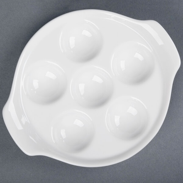 A white CAC China escargot dish with six holes.
