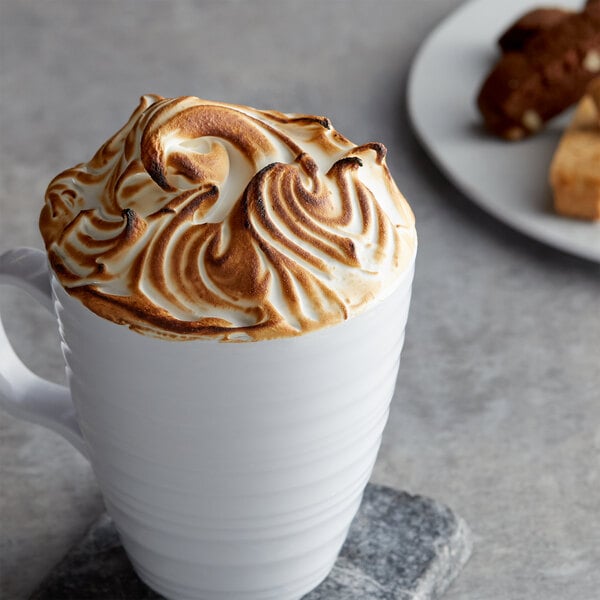 A white mug of coffee with brown and white foam on top.