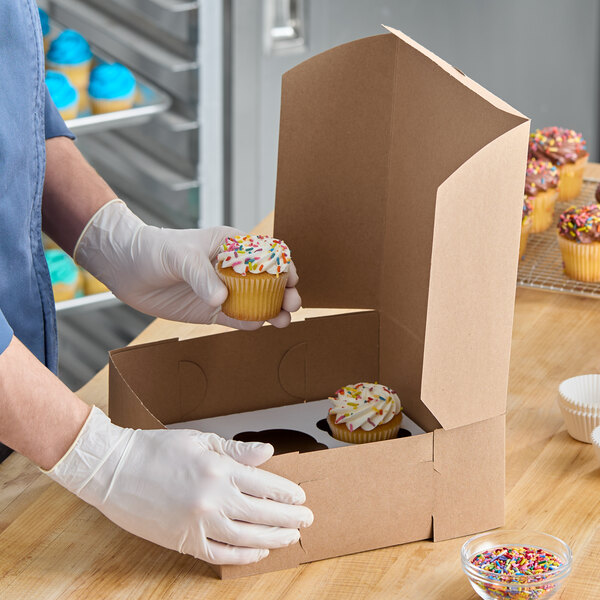 A kraft cupcake or muffin box with a 6-slot reversible insert being filled with cupcakes.