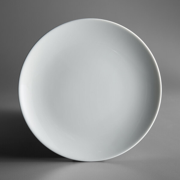 A Schonwald bone white porcelain coupe plate with a small rim on a gray surface.