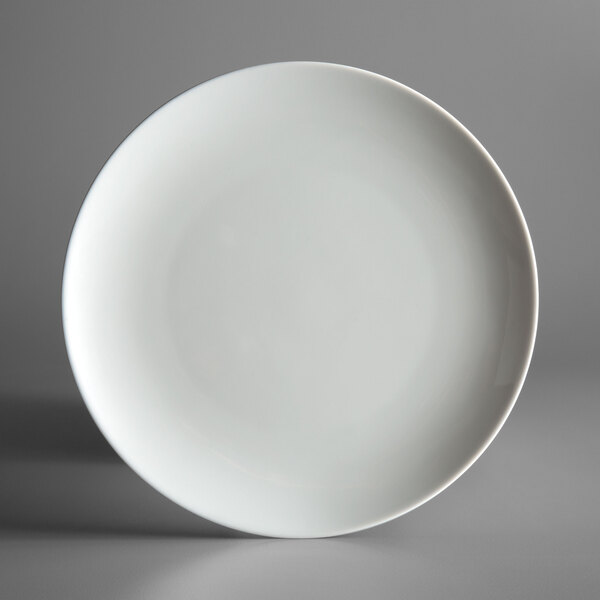 A Schonwald bone white porcelain coupe plate with a small rim on a gray surface.
