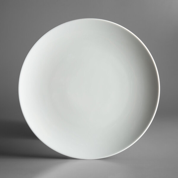 A Schonwald Allure bone white porcelain coupe plate with a rim on a gray surface.