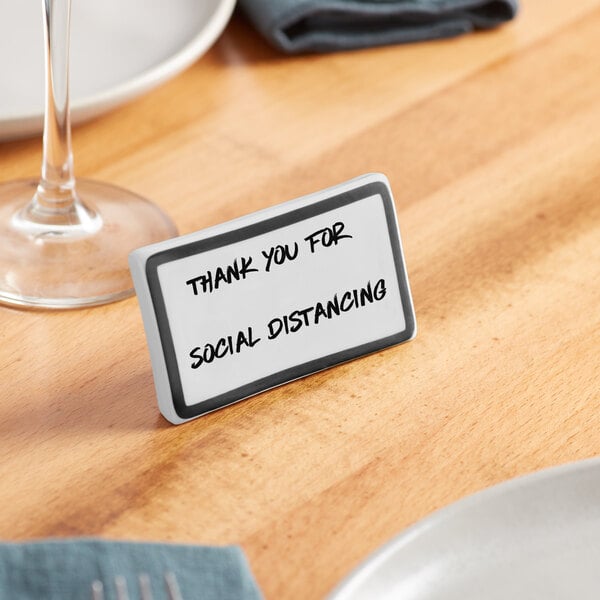 A black ceramic table tent sign with a decal border on a table.